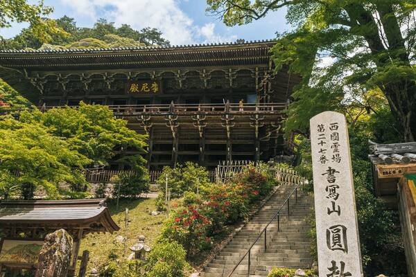 A traditional Japanese building with a wooden structure and a stone sign with Japanese characters.