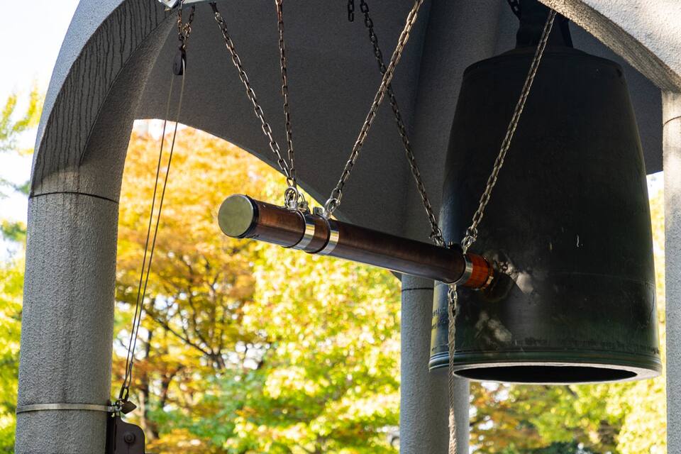 A large bell hanging from a stone structure with chains.
