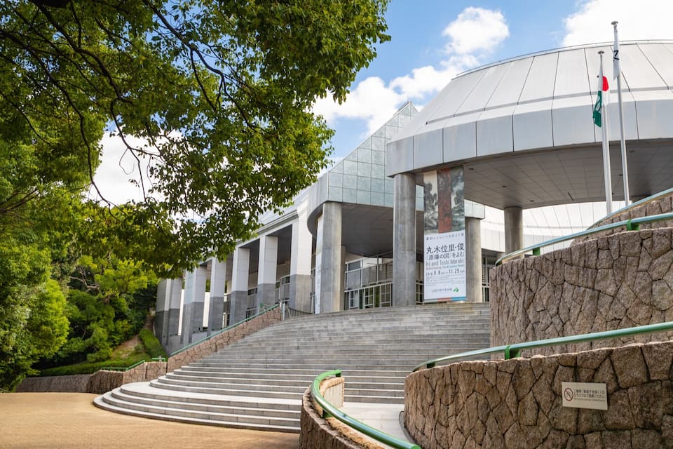 A modern building with a dome roof, stone steps, and a flagpole.
