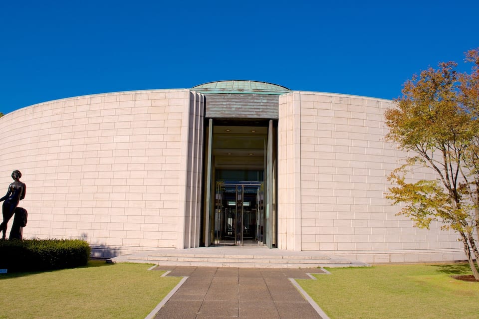 Ein rundes Gebäude mit Glastür und einer Statue davor.