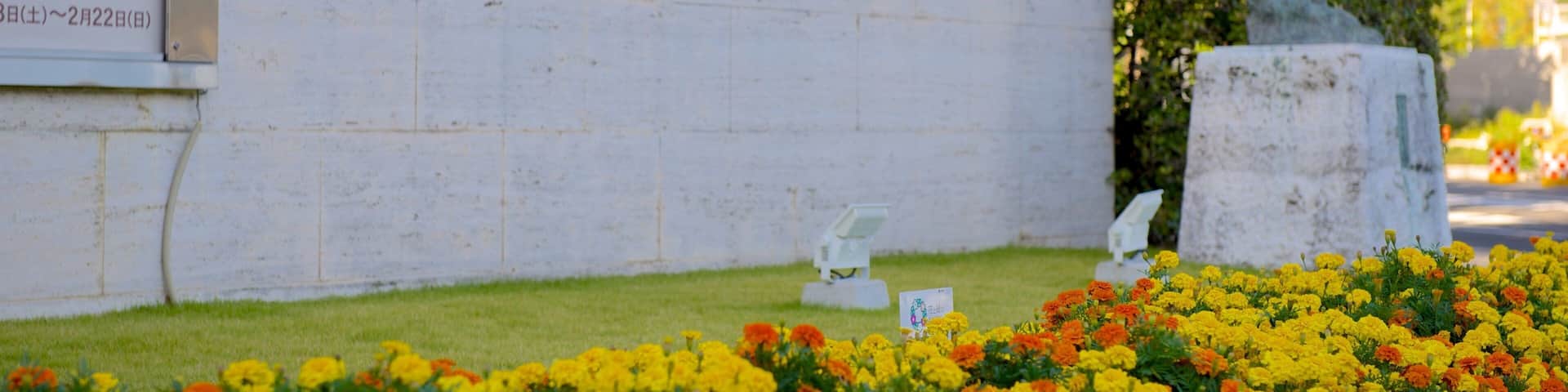 The Hiroshima Museum of Art sign with a statue of an angel and flowers in the foreground.