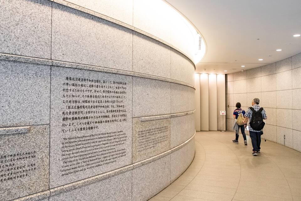 A curved wall with engraved text and a corridor with a tiled floor.