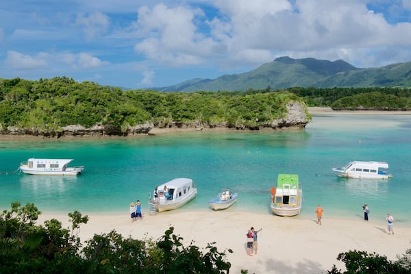 Kabira Bay Beach das einen Bootfahren und Strand sowie kleine Menschengruppe