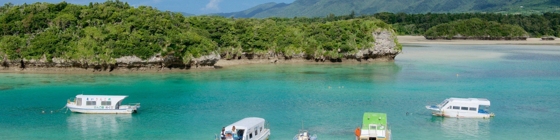 Kabira Bay Beach showing a sandy beach and boating as well as a small group of people
