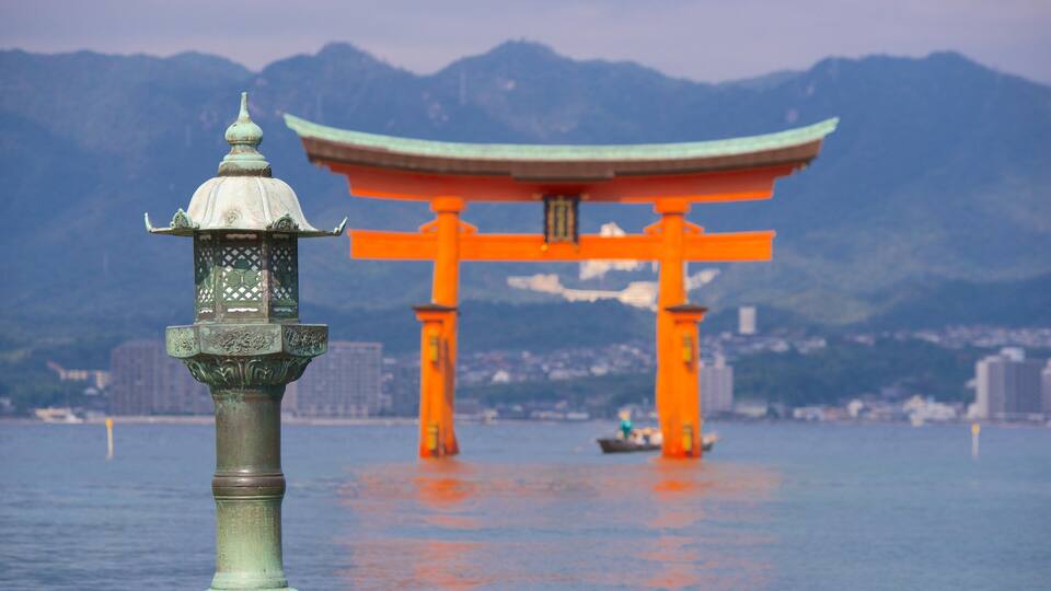 A traditional Japanese torii gate in the water with mountains in the background.