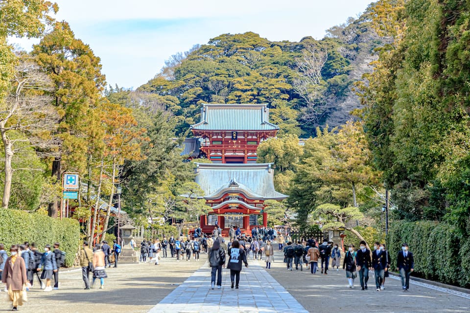 Una pagoda japonesa tradicional con varios niveles, rodeada de abundante vegetación y una multitud de personas.