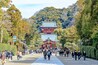 Una pagoda giapponese tradizionale con più livelli, immersa nel verde e circondata da una folla di persone.