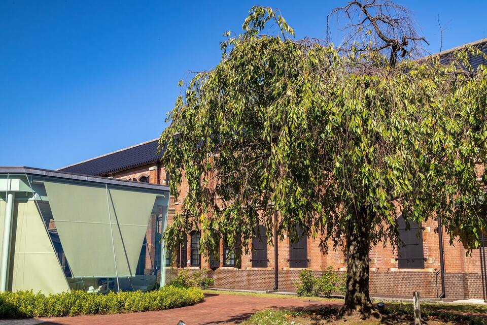 A modern building with a glass facade and a brick structure with windows.