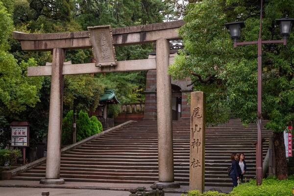 A stone torii gate with steps leading up to it, surrounded by lush greenery.