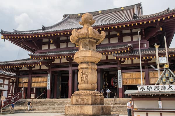A traditional Japanese building with a stone statue in front.