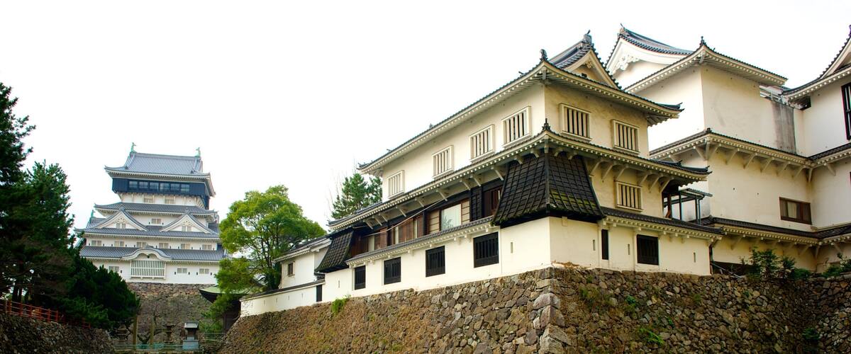 A traditional Japanese castle with a stone wall and a river in the foreground.