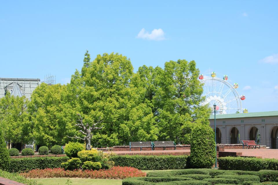 Un parc doté d’une grande roue, de bancs et de haies bien entretenues.