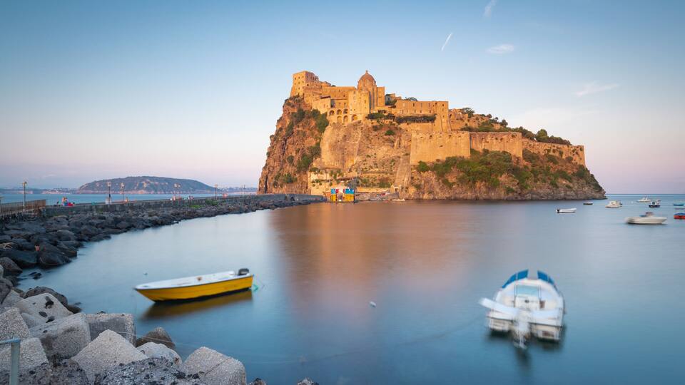 A coastal fortification with boats in the foreground.