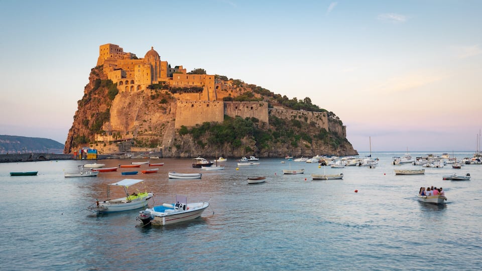 A coastal town with a historic castle on a cliff, surrounded by boats in the harbor.