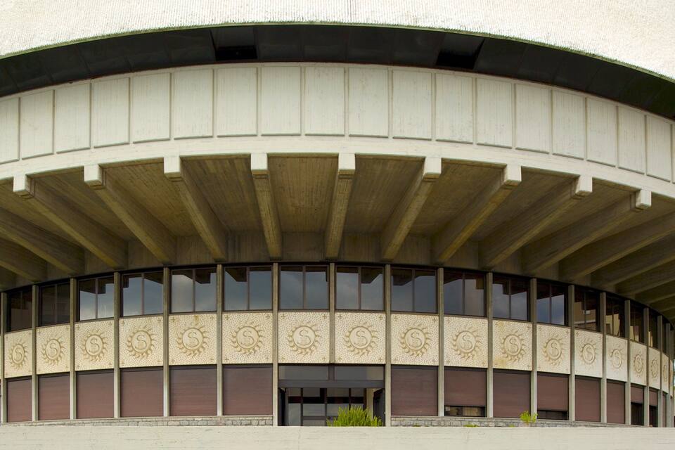 Un edificio grande y circular con techo curvo y paneles decorativos.