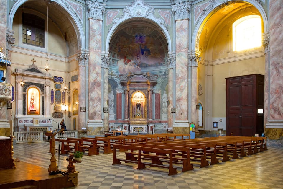 An ornate church interior with marble columns, a checkered floor, and a central altar.