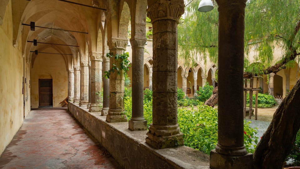 A historic cloister with stone columns, arches, and a tiled floor.