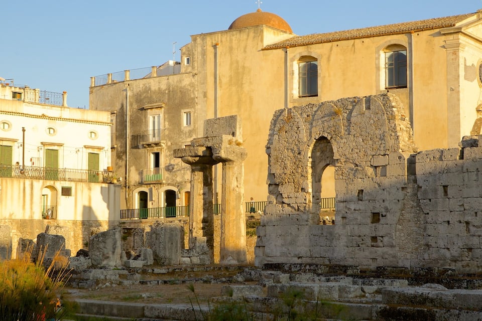 An ancient stone structure with arches and columns, adjacent to a modern building with a dome and windows.