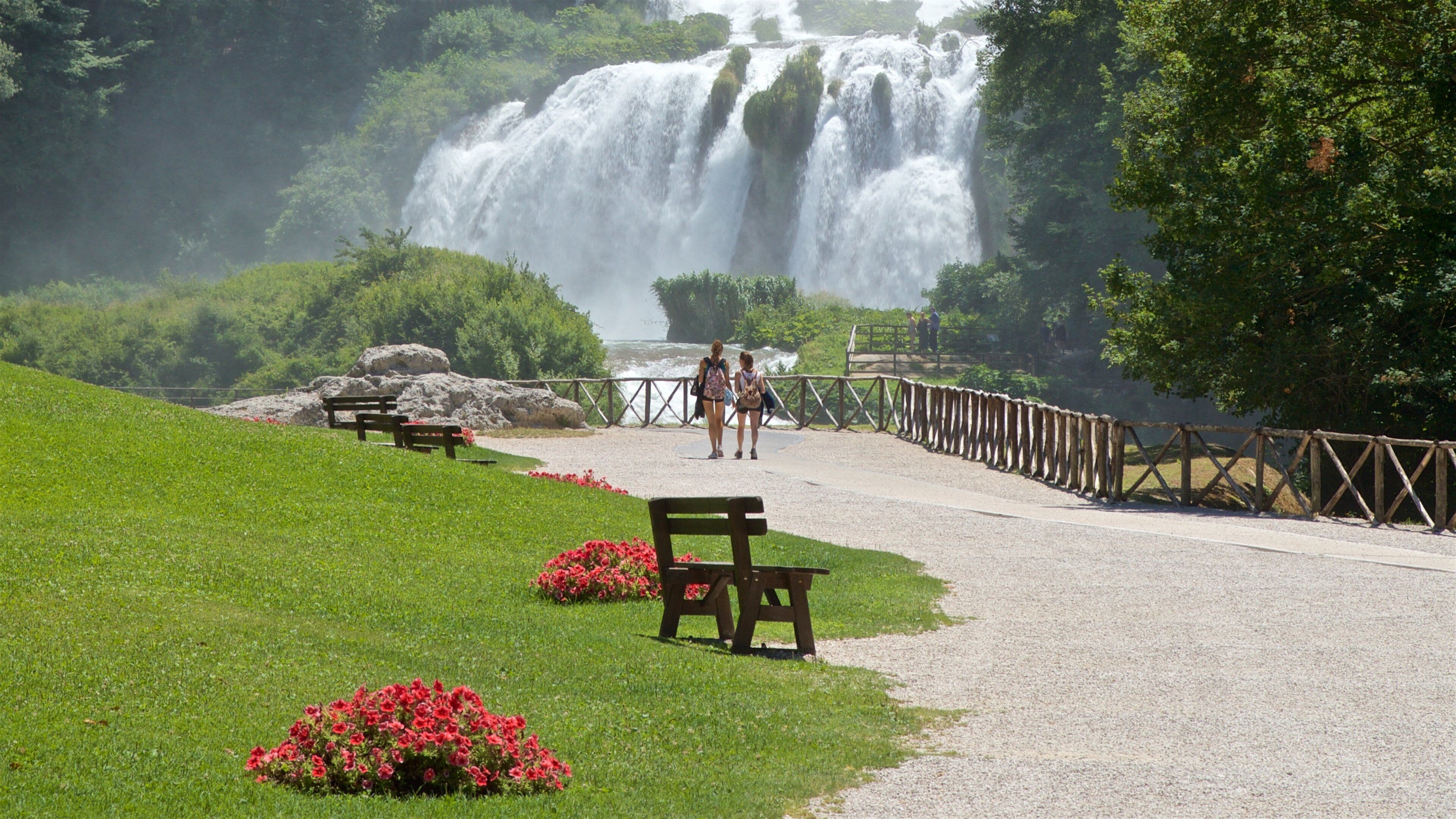 A waterfall, benches, and a path leading to it.