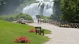 A waterfall, benches, and a path leading to it.