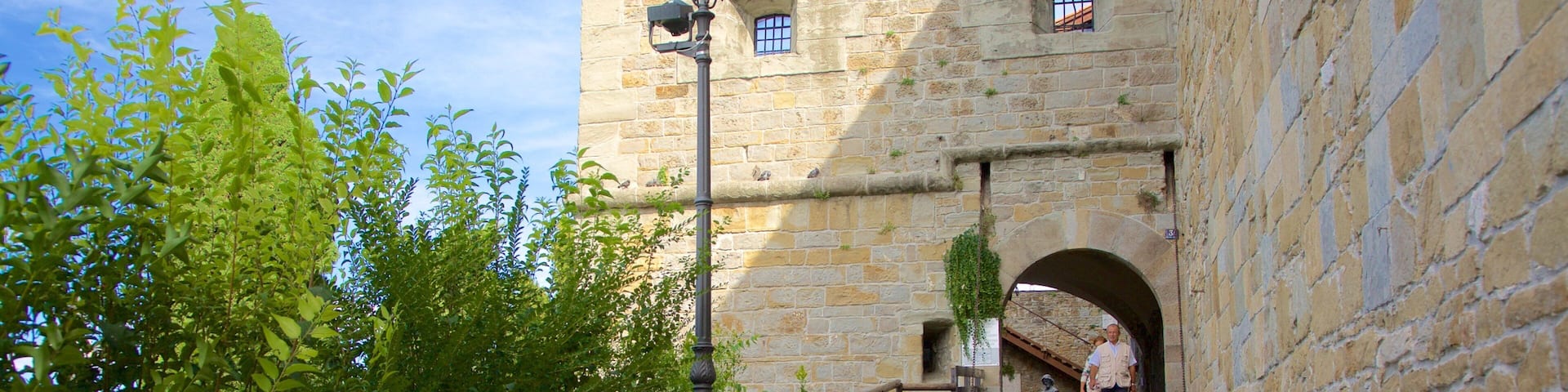 A stone pathway leading to a historic building with arched windows and a lantern post.