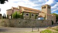 Um edifício histórico de pedra com uma torre de sino, janelas em arco e telhado com telhas.