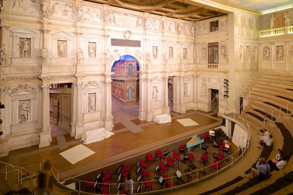 An ornate interior with classical architecture, including columns, statues, and detailed frescoes.