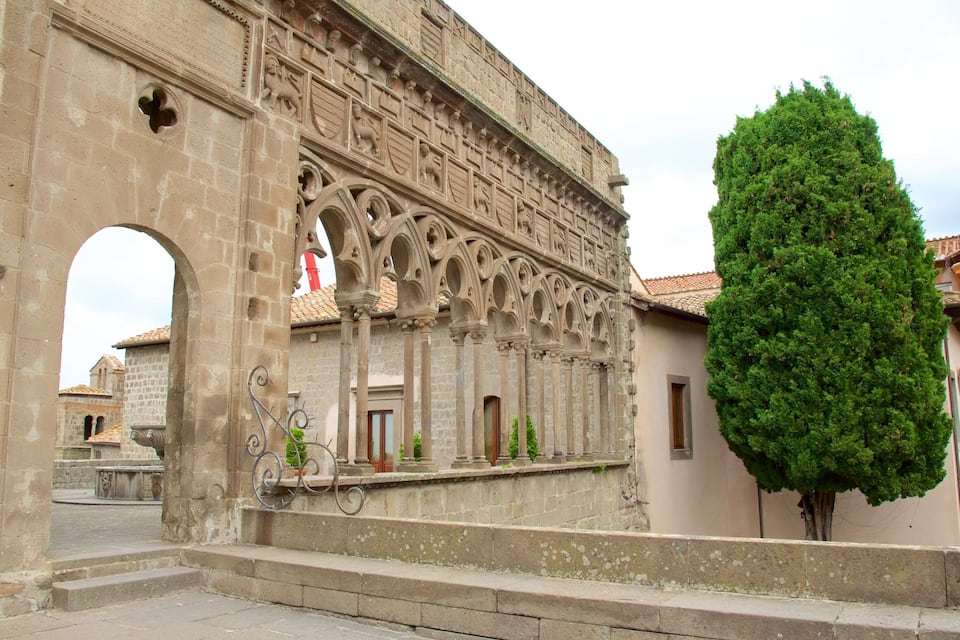 An old stone building with intricate carvings and a large tree in front.