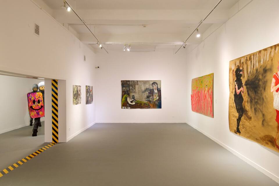 An art gallery with white walls and a gray floor. There are several paintings on the walls, including a large one of a woman in a red dress.