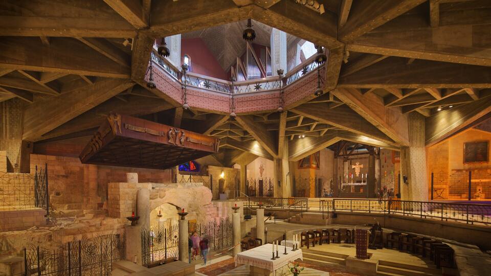 A grand interior with a high ceiling, stone walls, and a central dome.