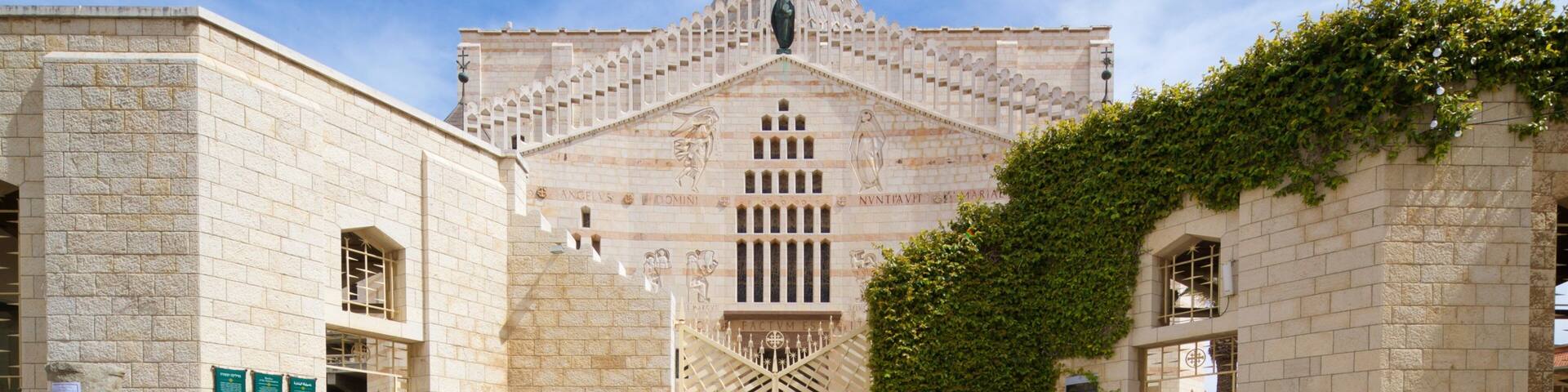 Un bâtiment historique doté d’un dôme central, flanqué de murs en pierre et d’un grand arbre.