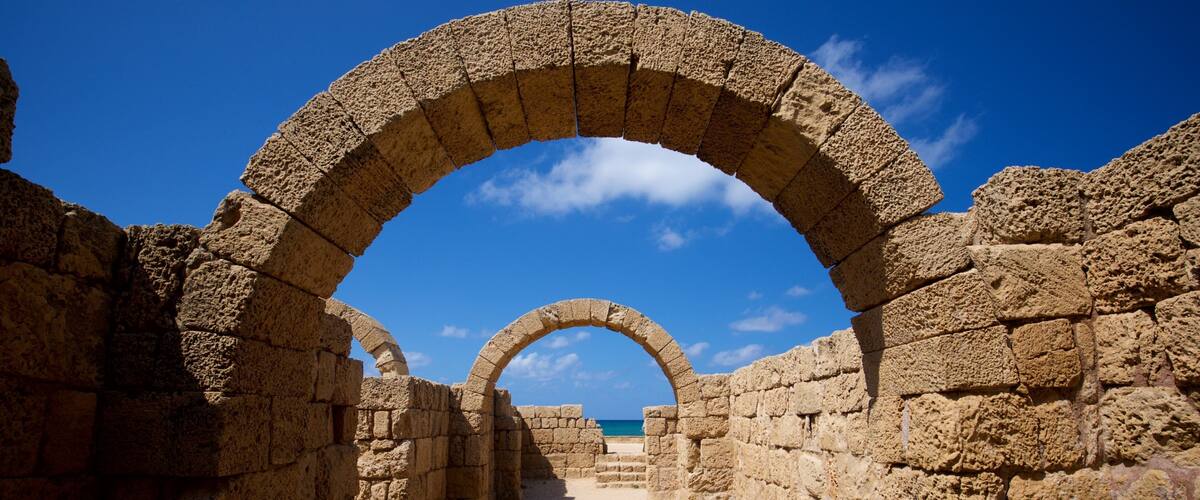 An ancient stone archway leading to a beach.