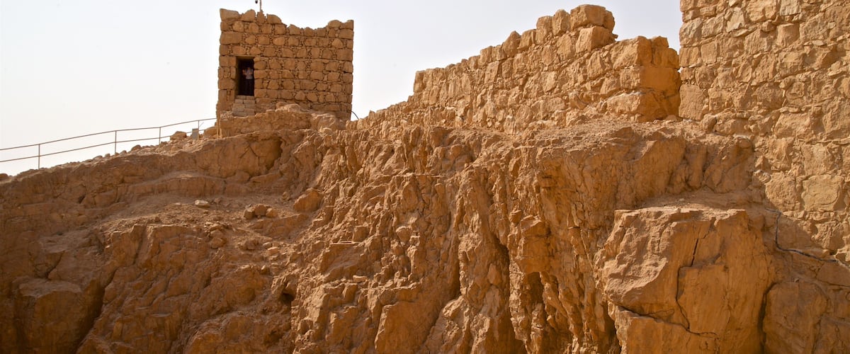 A rocky landscape with ancient stone ruins and a small building with an open doorway.