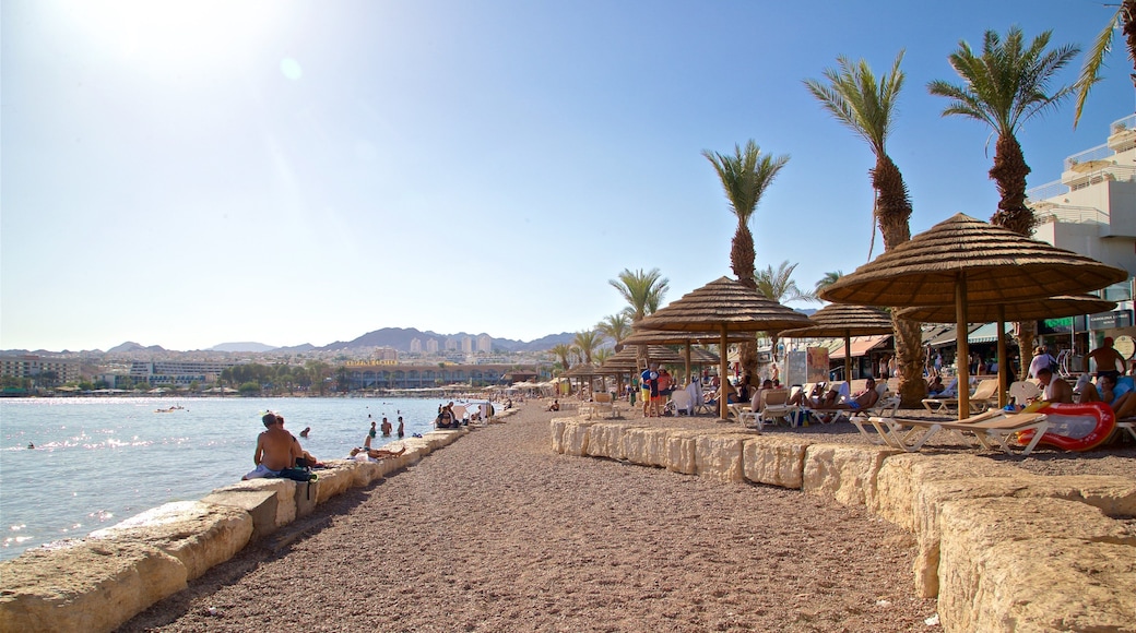Green Beach showing a sandy beach and general coastal views as well as a small group of people