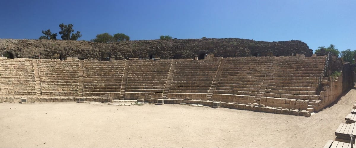 An ancient amphitheater with stone steps and a central stage area.