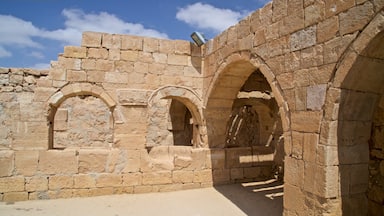 An ancient stone structure with arched passageways and a stone wall.