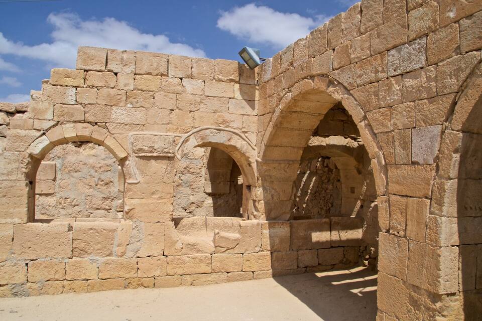 Eine alte Steinarchitektur mit gewölbten Gängen und einer Steinmauer.