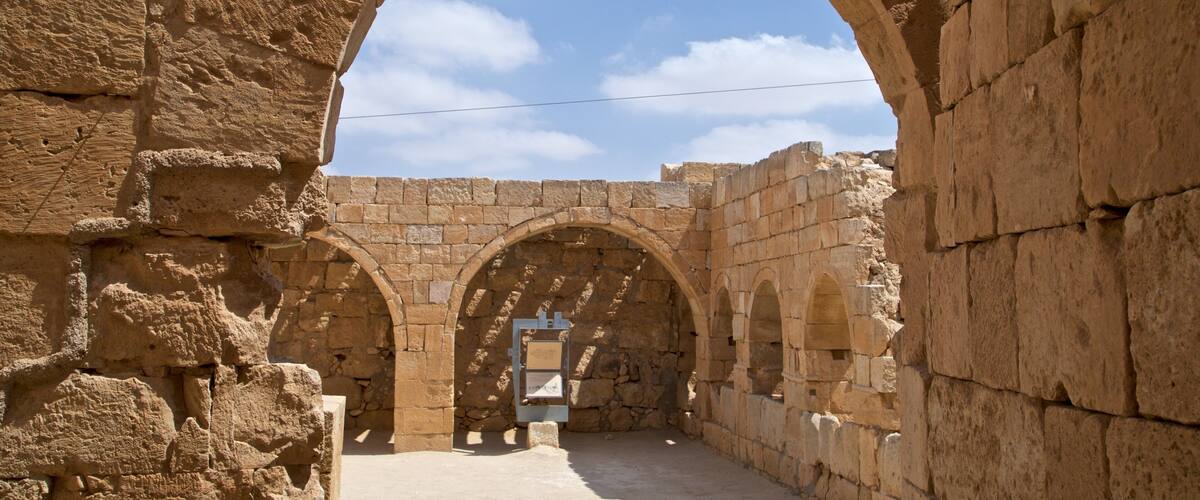 An ancient stone archway with a clear blue sky in the background.