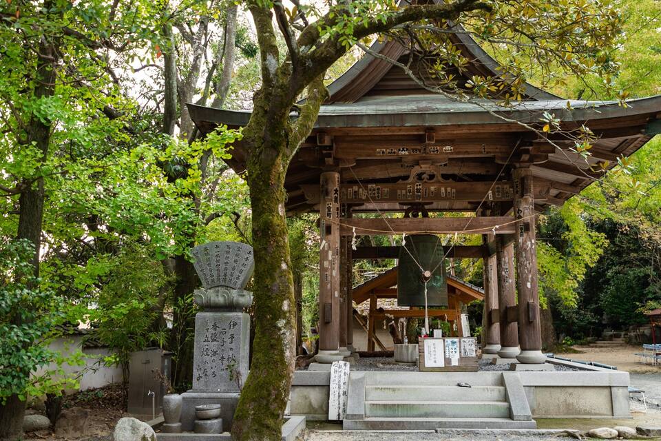 Un santuari japonès tradicional amb estructura de fusta, fanals de pedra i inscripcions.