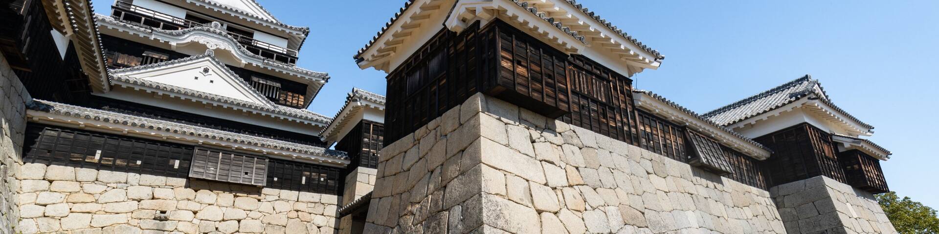 A traditional Japanese castle with stone walls and multiple tiled roofs.