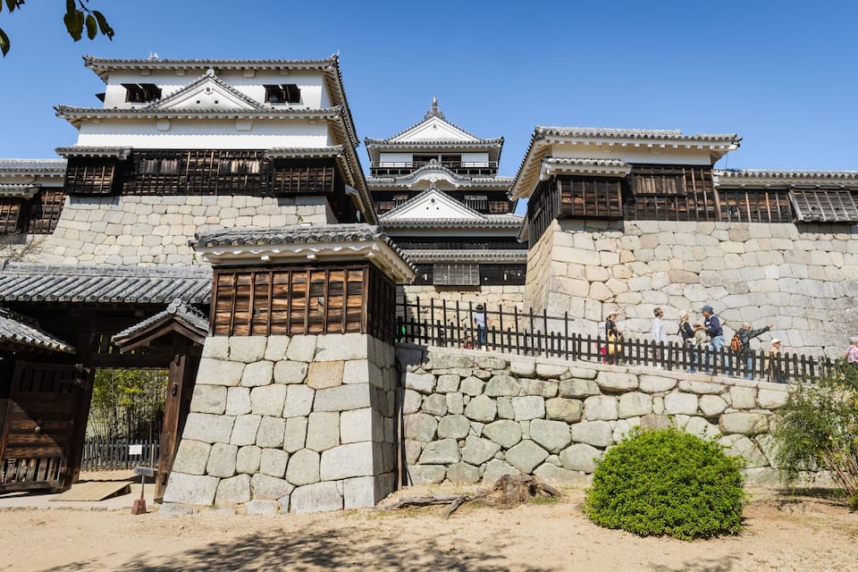 A traditional Japanese castle with stone walls and multiple levels of roofs.