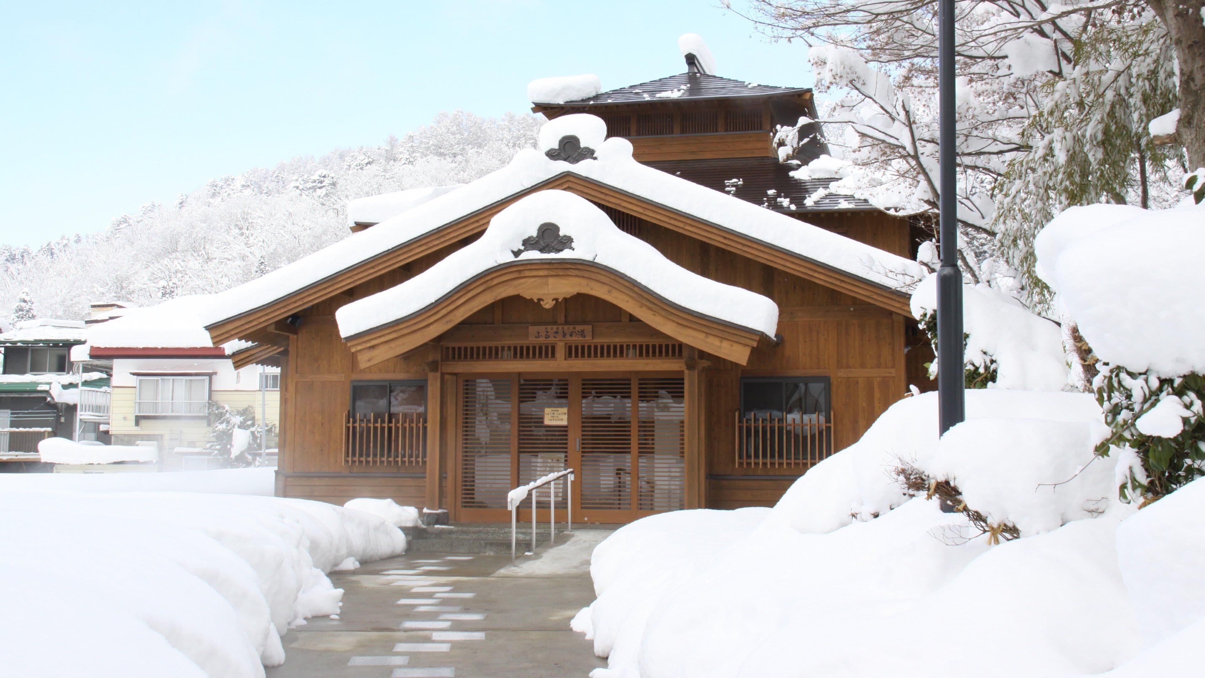 A wooden building with a snow-covered roof and steps leading up to it.