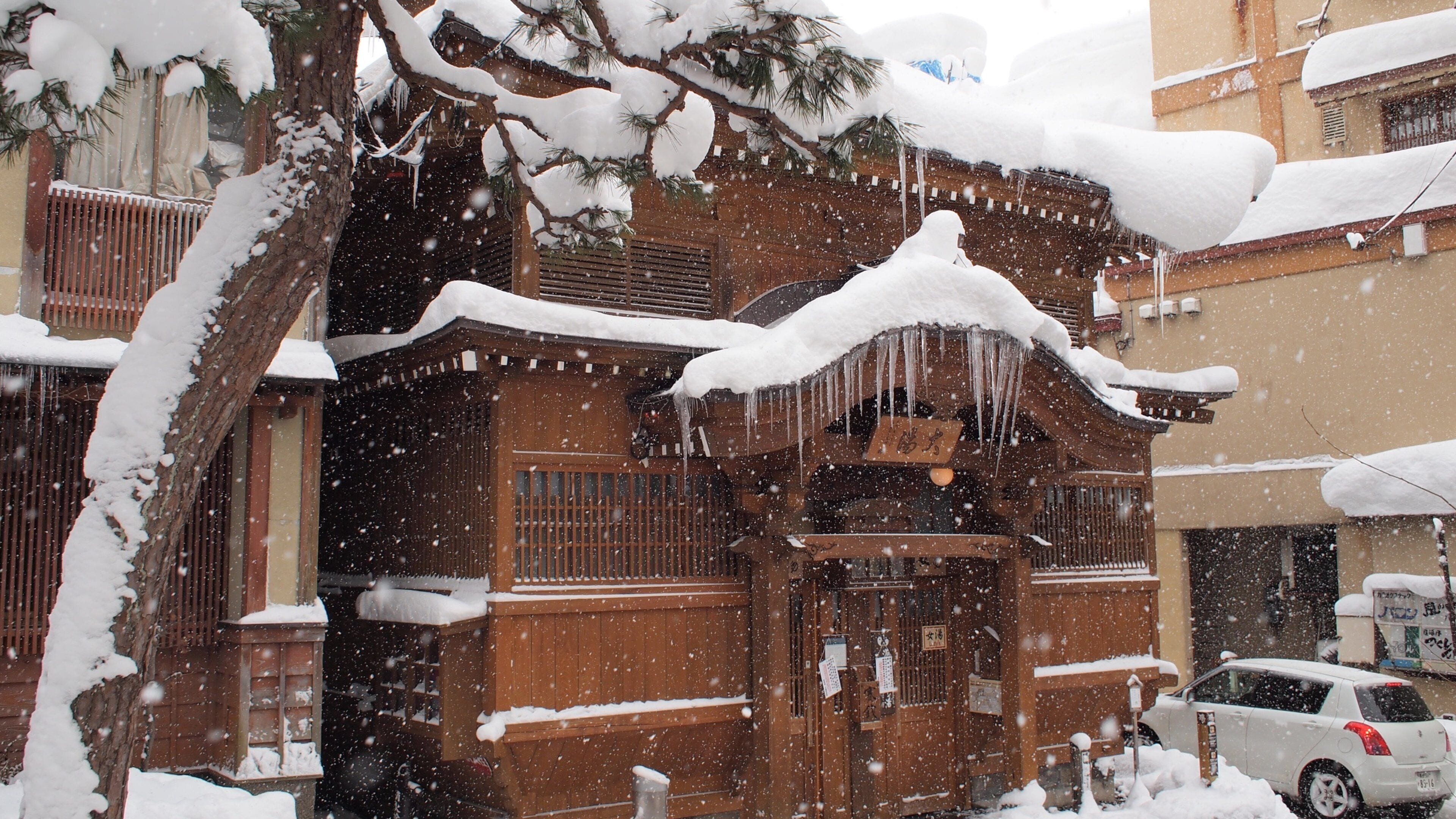 A traditional wooden building with snow-covered eaves and icicles.
