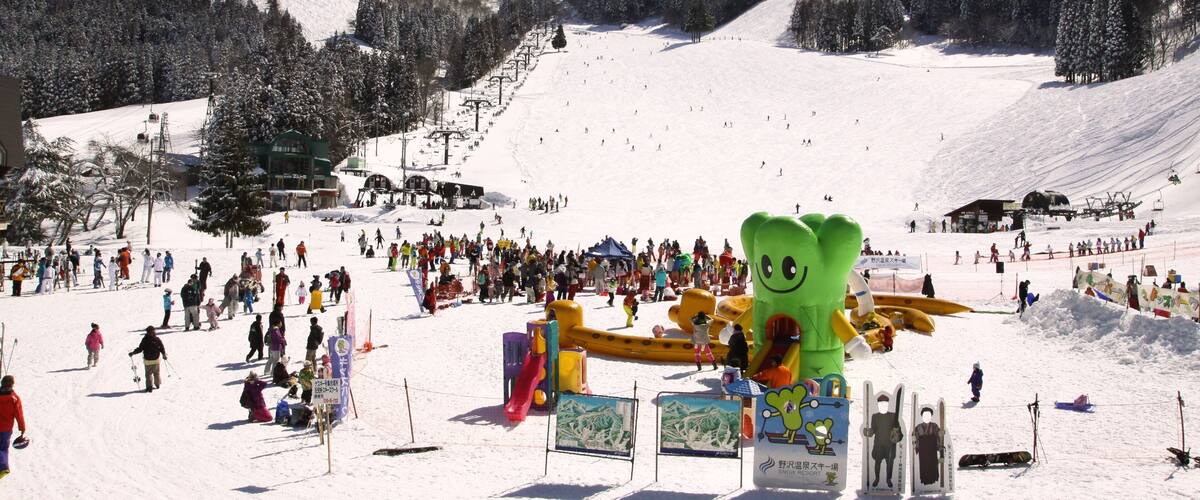A snowy ski resort with a large inflatable character, ski lifts, and a mountain backdrop.