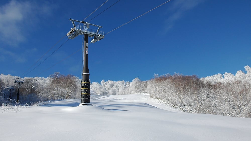 A snow-covered landscape with a ski lift and trees.