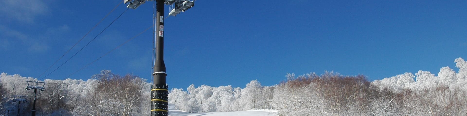 A snow-covered landscape with a ski lift and trees.