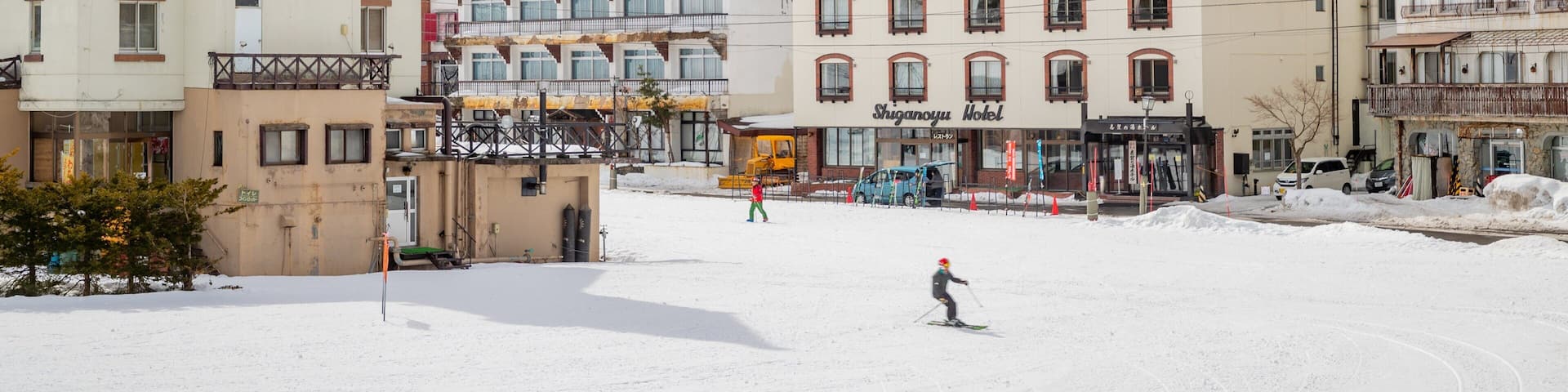 A snowy town with a clock tower, a ski resort, and a mountain backdrop.