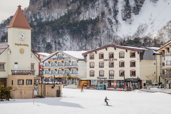 A snowy town with a clock tower, a ski resort, and a mountain backdrop.