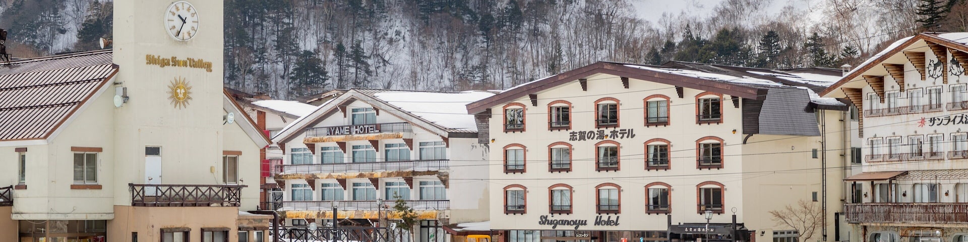 A snowy town with a clock tower, a ski resort, and a mountain backdrop.