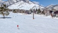 Skiers on ski slope with jagged mountain backdrop. Hakuba, Japan